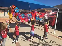 Students holding a dragon decoration at a parade.