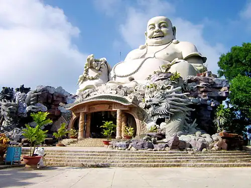 Statue of Maitreya in Budai form surrounded by a dragon on Cấm Mountains, Vietnam