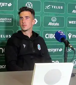 Man sitting during a press conference in front of a microphone and looking to his right