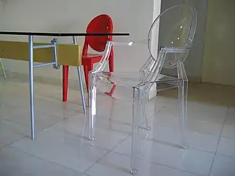 Chairs designed by Philippe Starck for Kartell: a transparent "Louis Ghost" in the foreground and a red "Victoria Ghost" in the background