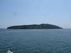 A coastal view of Tashirojima with forested hills and calm sea