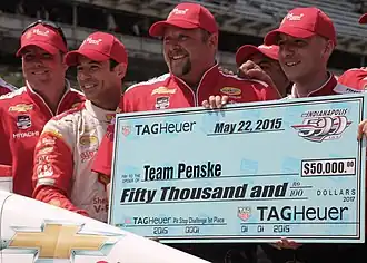 Crew members employed by Team Penske holding a large cheque for $50,000