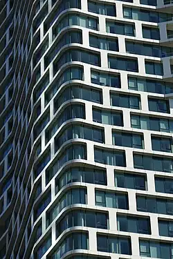 Architectural detail of ARO's facade. The undulating white walls have windows of different widths and uniform height.