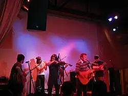 Band onstage, including a violinist and a trumpeter