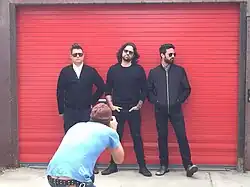 Crash Kings being photographed with a red-orange store shutter behind them