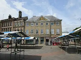Three storey dressed stone building with many windows against a bright blue sky