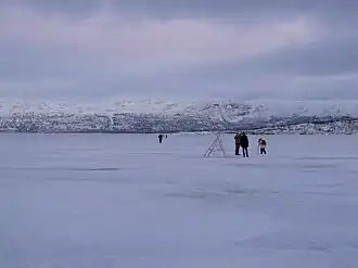 Frozen Torneträsk lake, with people walking and taking pictures on its surface (Jan 2013)