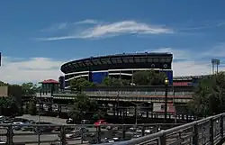 View from the Mets-Willets Point station's platform, with the former Shea Stadium in the background. A black fence, which surrounds the platform, is visible on the bottom right corner.