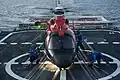 Flight deck crew members aboard Bertholf tie down an MH-65 Dolphin helicopter.