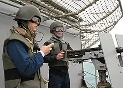 Petty officers wearing Mark 4 talker helmets manning a machine gun turret aboard the USS Tarawa (LHA-1) in 2003