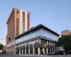 A squat, modern building of steel, glass, and concrete pillars is shown attached to the back of a taller and much older building clad in brick and stonework. The nearer building has signage, "Paterson GlobalFoods Institute