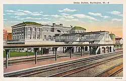 A postcard view of railway station platforms and a large brick station building