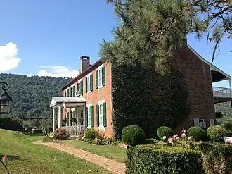 Side view of two-story brick house with green shutters