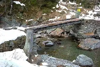 Log bridge in France with dry set stone abutments and a footpath leveled with boards