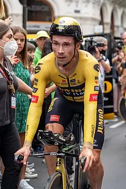 Roglič on a time trial bike, wearing a yellow and black areo-helmet and jersey.