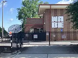 The W A B E letters, but in a square, on a midcentury brick building with a visible satellite dish