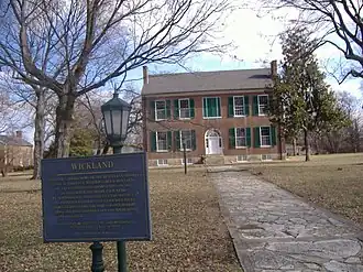 A two-story mansion with a historical marker in the foreground