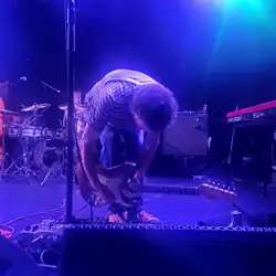 Ira Kaplan bent over a series of guitar pedals