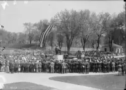 Black and white photograph of people gathered around the statue. Healy Hall is in the background; its entrance is draped in patriotic bunting
