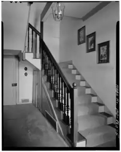 Carpetted stairwell with dark wood railing and three pictures on the wall